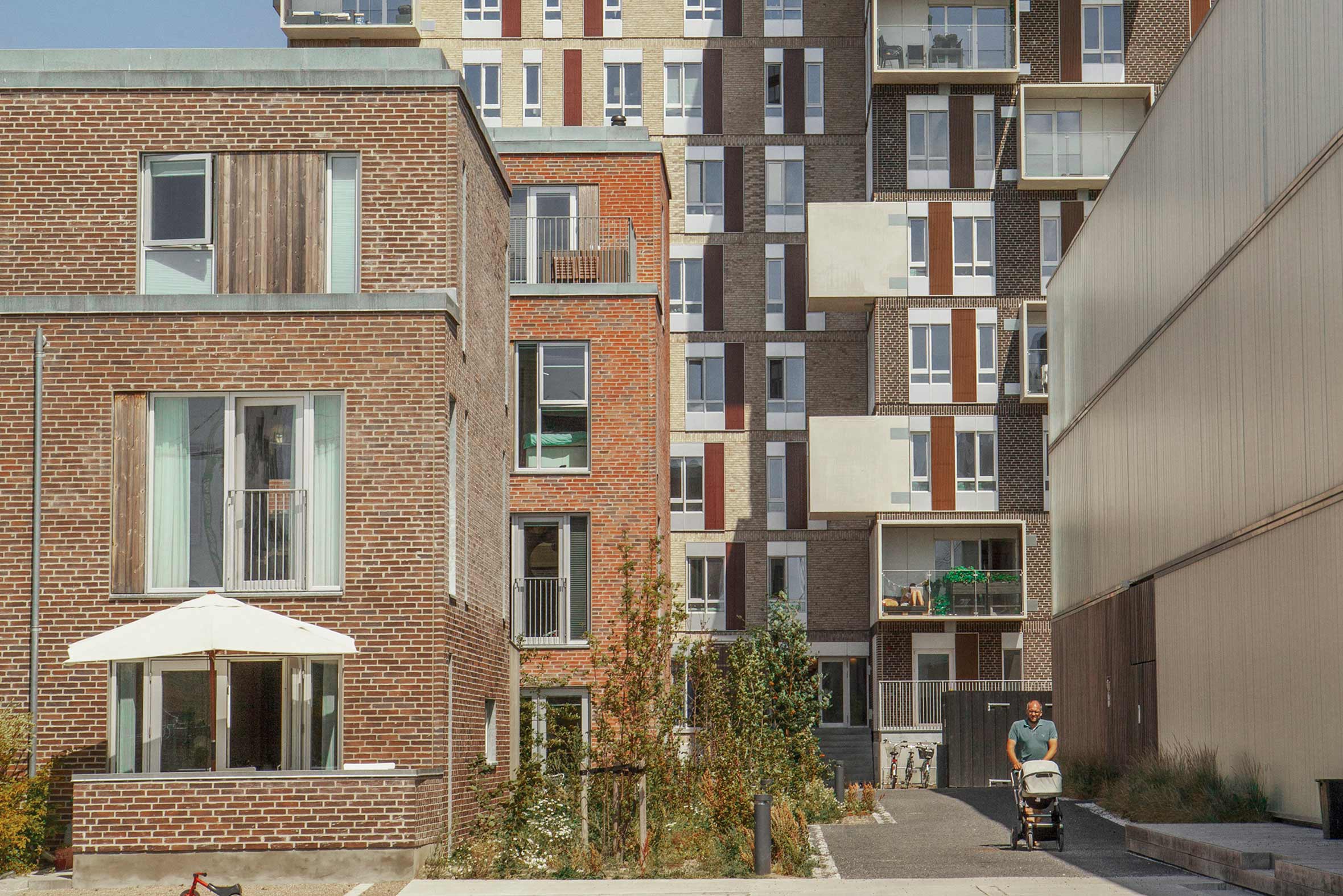 Rækkehuse i rød mursten med egen terrasse og lejligheder i baggrunden