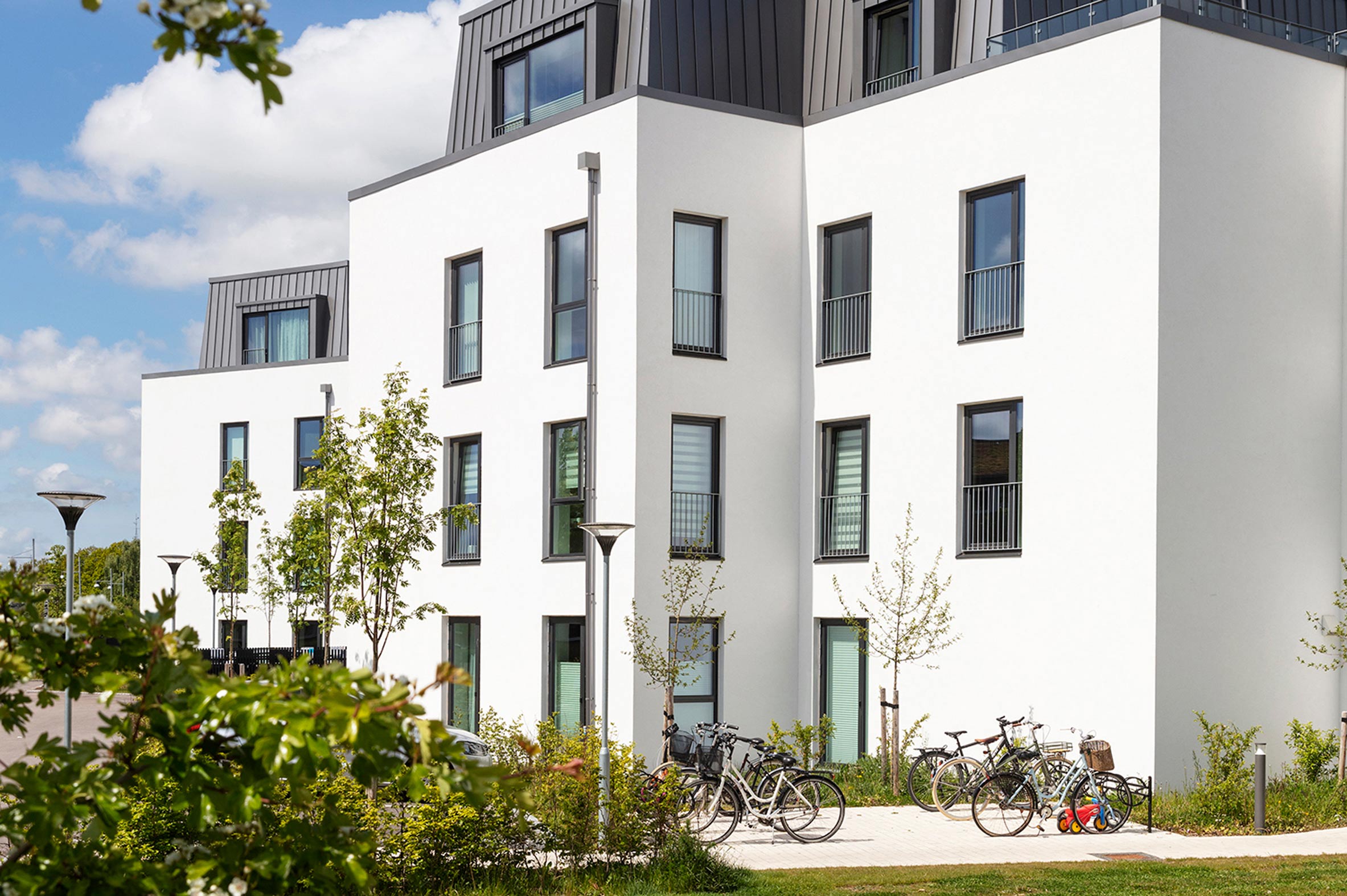 Nybyggede lejligheder med parkering til både biler og cykler i grønt område
